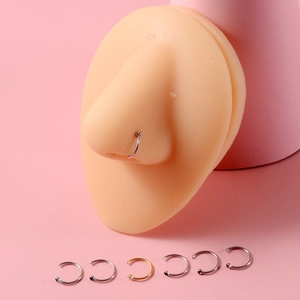 Close-up of colorful C-shaped stainless steel nose rings with cubic zirconia on a model