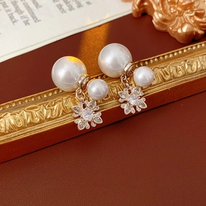 Detail of floral gold earrings with pearls and crystals on vintage red leather background