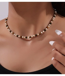 Detail of beaded necklace with tiger eye stones worn by a model on neck