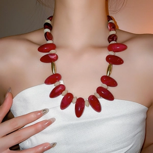 Detail of red teardrop beads and gold accents on a bohemian choker necklace