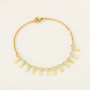 Detail of gold chain bracelet with green beads and round drops on plain background