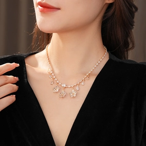 Close-up of gold flower and teardrop pendant necklace with sparkling zircon crystals