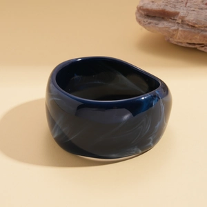 Macro detail of dark blue resin bangle showing artistic white marble textures and glossy finish