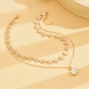 Double-layered gold necklace featuring white daisy flower pendants and an elegant lobster clasp