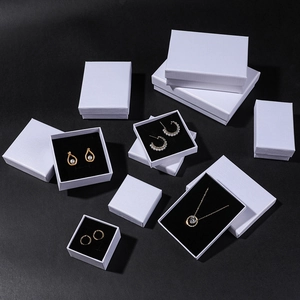 Set of white textured jewelry gift boxes with black lining on a dark background