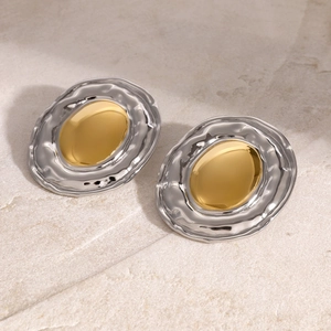 Detailed macro view of two-tone oval earrings with gold center and silver hammered texture
