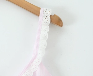 Macro detail of white lace trim on pink striped shoulder strap with high texture