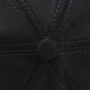 Detailed macro view of black cotton baseball cap crown with reinforced stitching and top button