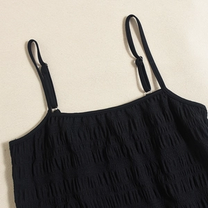 Detail of adjustable thin spaghetti straps and ruched fabric texture on a black top