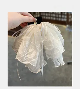 Détail de la pince à cheveux en dentelle blanche avec perles et rubans pour un style élégant