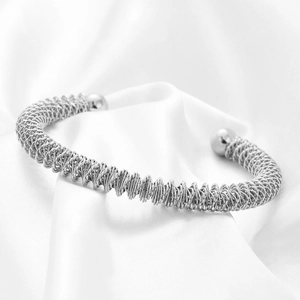 Macro di bracciale a molla intrecciata placcato oro 18 carats su seta bianca morbida