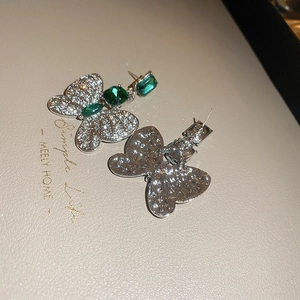 Vue détaillée des boucles d'oreilles papillon avec gemme verte et cristaux pavés blancs