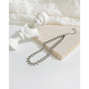 Macro detail of silver wheat-style chain link with lobster clasp on elegant stone base