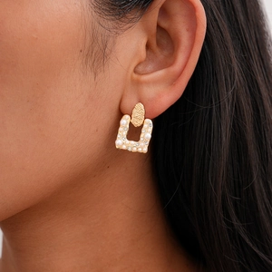 Elegant gold U-shaped earrings set with white pearls and sparkling crystals on model