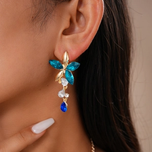 Détail de boucles d'oreilles à pompons fleurs vintage avec cristaux bleus sur modèle