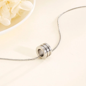 Close-up of a silver cylinder pendant with triple-ring design and diamond inlay on chain