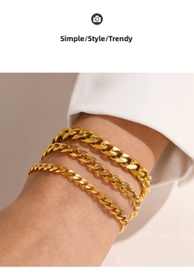 Close-up of three gold-plated stainless steel Cuban link bracelets worn on a wrist
