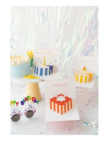 Close-up of 3D birthday cake greeting cards and colorful party glasses on foil background