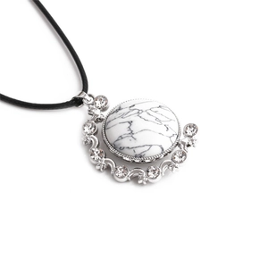 Detail of round white marble pendant with crystals and stars on black cord necklace