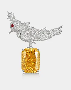 Detalle del broche de pájaro sobre una roca con gema amarilla y motivo de pájaro de cristal