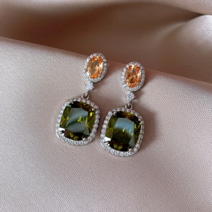Vue détaillée de boucles d'oreilles aux pierres orange et vert olive sur de la soie