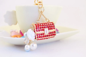Detail of red rhinestone camellia bag keychain with white rose and pearls decor