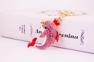 Close-up of a pink rhinestone dolphin keychain with gold crown and red crystal accents
