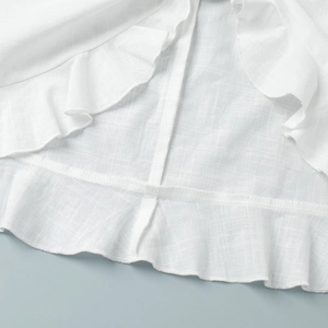 Detail of white ruffle trim and textured cotton-linen fabric with precise stitching