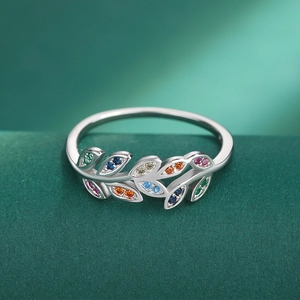 Macro shot of silver olive branch ring with colorful zircon stones on green velvet