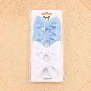 Detail of four fabric bow hair clips in blue and white on a fashion display card