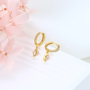 Detail of gold huggie hoop earrings with marquise-cut zircon and small inlaid diamonds
