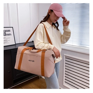 Detailed view of large travel bag with wide orange straps and black brand logo