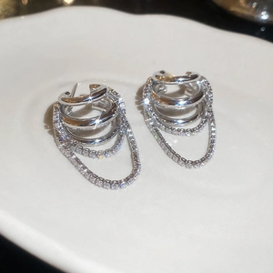 Détail de boucles d'oreilles multicouches en argent avec zircons et pompons