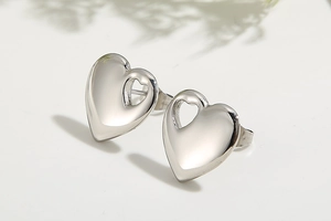 Detail of silver heart-shaped stud earrings with smooth finish and cutout design