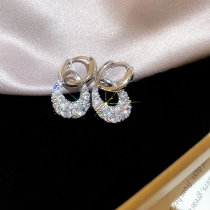 Macro shot of silver C-shaped drop earrings featuring sparkling inlaid cubic zirconia