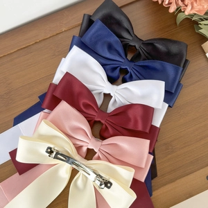 Elegant silk satin bow hair clips in six colors arranged on a rustic wooden surface