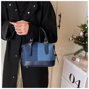 Dettaglio di borsa a mano patchwork in denim con finiture dorate in un ambiente domestico