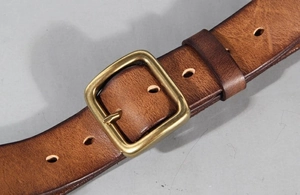 Detail of dark brown leather belt with vintage brass buckle and natural texture