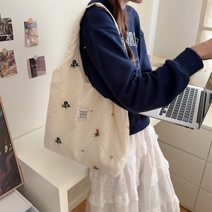 Detailed embroidery of floral pattern on a beige canvas tote bag with garden flower label