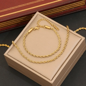 Detail of a gold rope chain bracelet with lobster clasp on a beige jewelry gift box