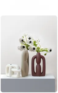 Close-up of three modern Nordic matte ceramic vases in geometric hollow shapes for decor