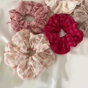 Flat lay of five assorted lace and plaid oversized hair scrunchies on white fabric