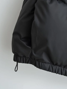 Detail of black puffer vest featuring adjustable drawstring hem and premium windproof fabric