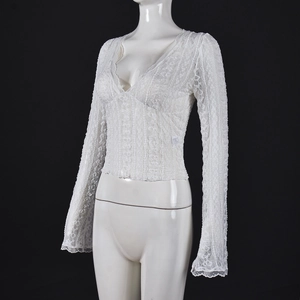 Detailed view of sheer white lace top with plunging V-neckline and flared sleeves