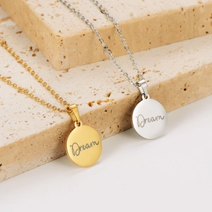 Engraved Dream pendant necklaces in 18k gold and silver on a minimalist stone base