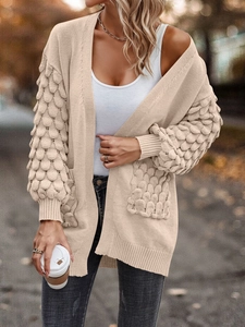 Close-up of beige knit cardigan showing 3D bubble stitch details and ribbed cuffs