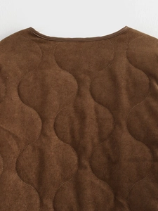 Detail van bruine corduroy stof met golfpatroon stiksels en afgewerkte halslijn