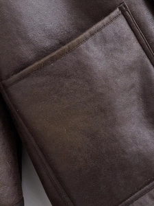 Close-up of deep brown leather jacket pocket featuring precise stitching and texture