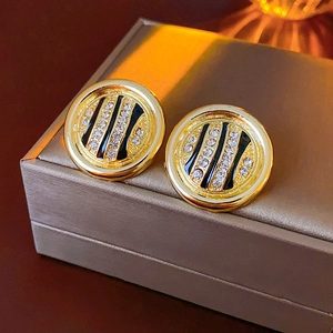Close-up of golden round stud earrings with zebra pattern and sparkling rhinestones