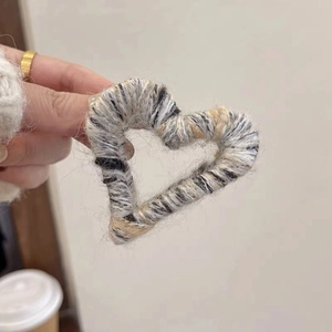 Detail of a gray heart-shaped plush knit hair claw clip featuring warm wool texture